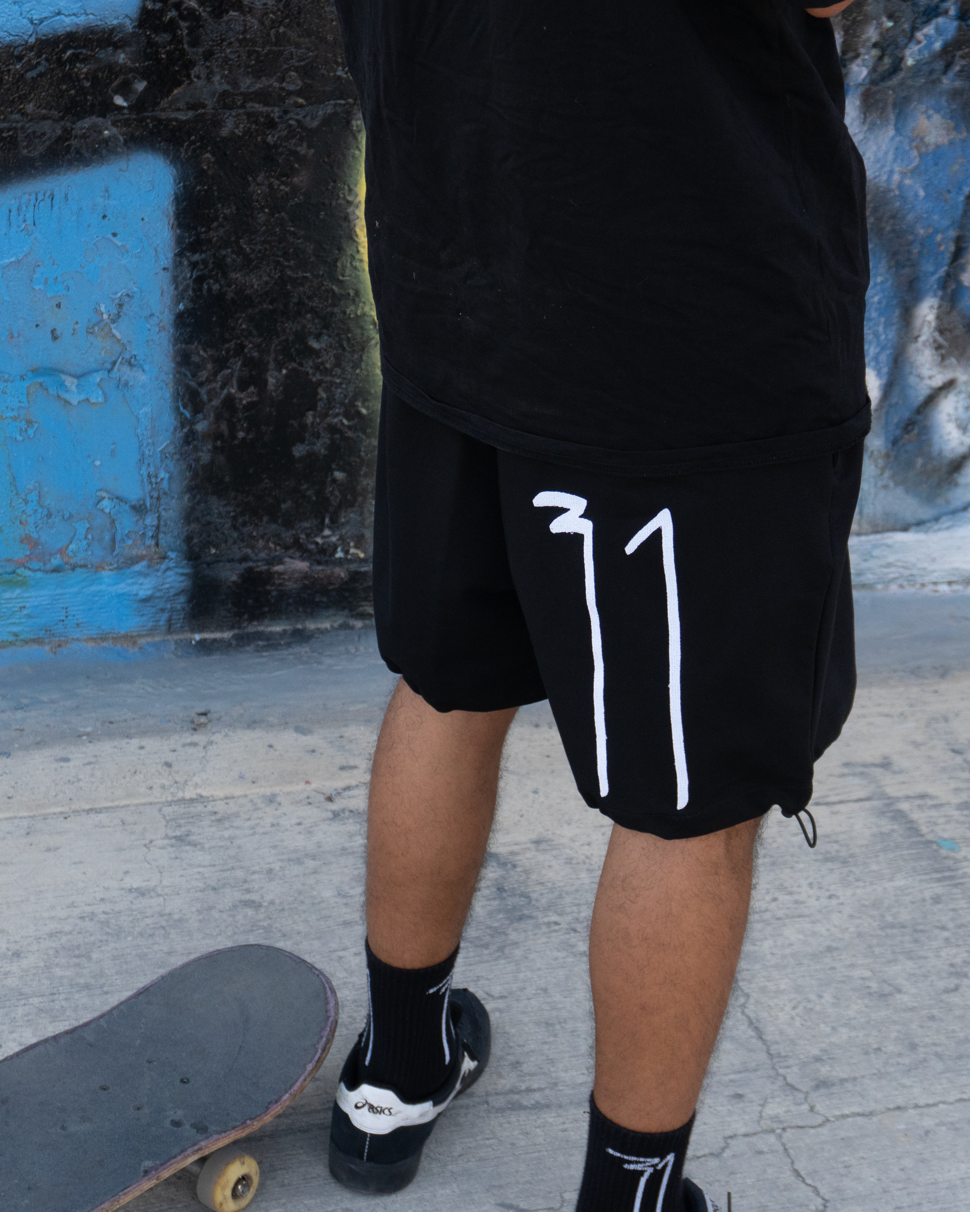 Close-up of OKRUG 31 black shorts with white 31 logo in a skatepark setting