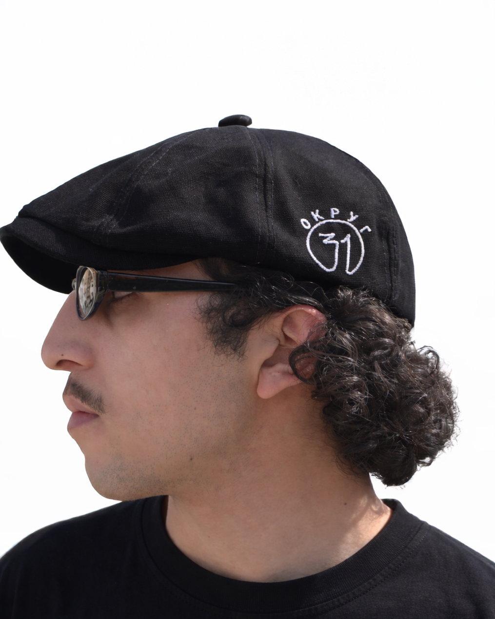 Man wearing a black cap with a logo on a white background